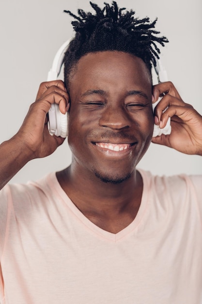 Homme afro-américain souriant dans les écouteurs écoutant de la musique sur fond gris
