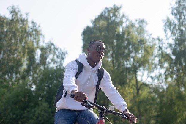 Un homme afro-américain souriant fait du vélo dans un parc public Sports et loisirs