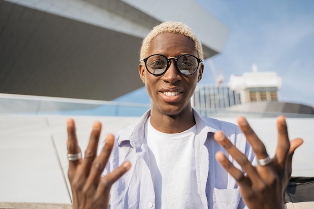 Homme afro-américain souriant portant des lunettes élégantes ayant un appel vidéo, communication en ligne