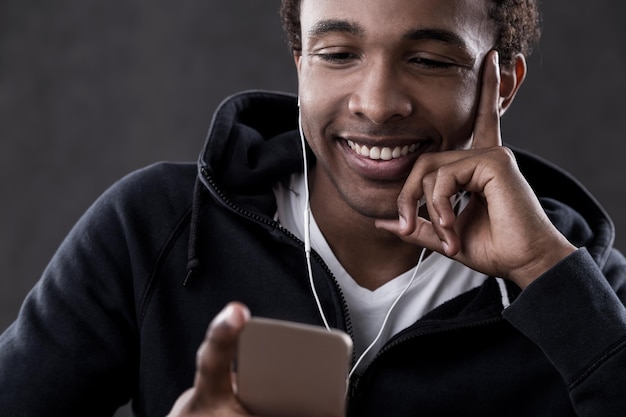 Homme afro-américain souriant regardant l'écran du téléphone