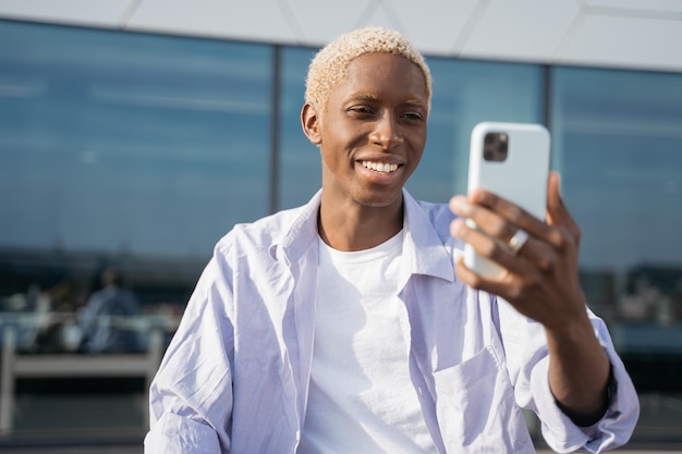 Photo homme afro-américain souriant utilisant la communication par téléphone portable, lisant des sms, faisant des achats en ligne