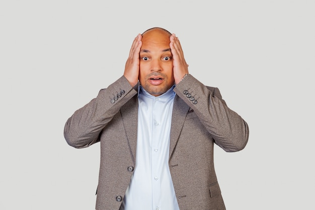 Homme afro-américain tenant les mains sur la tête avec une excitation heureuse, je ne peux pas croire les bonnes nouvelles