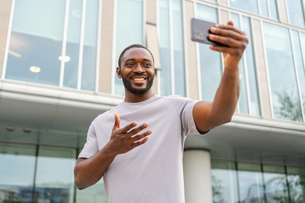 Un homme afro-américain tenant un smartphone en train de discuter en vidéo dans une rue urbaine en ville