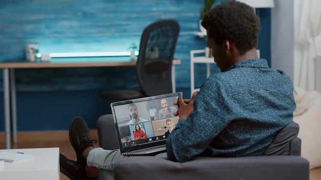 Homme afro-américain utilisant un ordinateur portable pour une conférence Internet en ligne avec ses collègues de travail à distance...