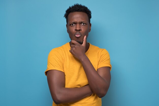 Homme afro-américain en vêtements jaunes et lunettes pensant ou planant