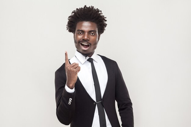 Homme afro de bonheur regardant la caméra avec le doigt d'idée. Prise de vue en studio, fond gris