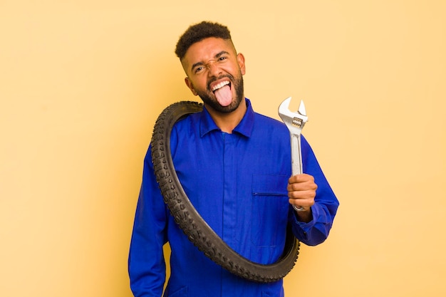 Homme afro cool avec une attitude joyeuse et rebelle plaisantant et tirant la langue sur le concept de réparateur de vélo