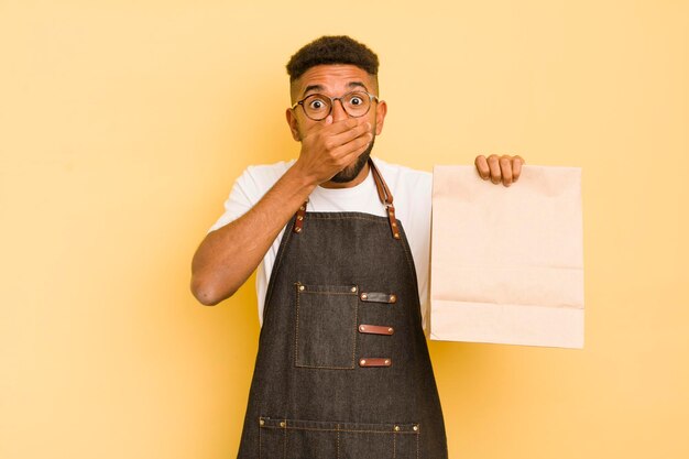 Homme afro cool couvrant la bouche avec les mains avec un livreur choqué et un concept de restauration rapide