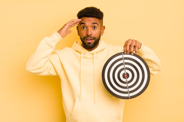 Homme afro cool à la recherche de concept de cible de fléchettes étonné et surpris heureux