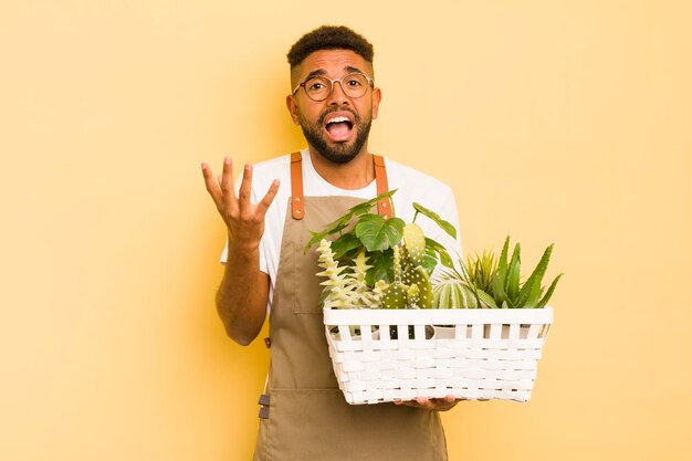 Homme afro cool à la recherche désespérée de jardinier et de plante frustré et stressé