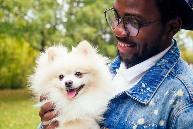 Homme afro étreignant son spitz moelleux dans le parc