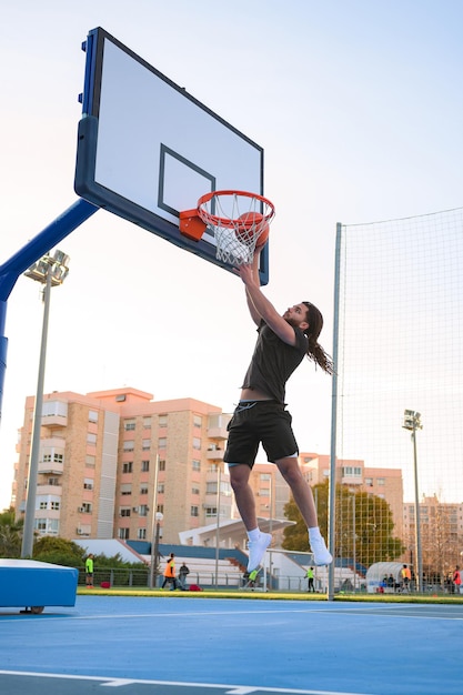 Un homme afro-latino joue au basket et plonge le ballon dans un panier