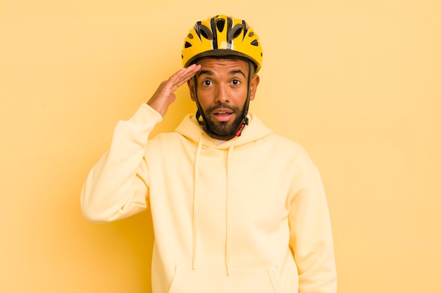Homme afro noir à la recherche de concept de vélo étonné et surpris heureux