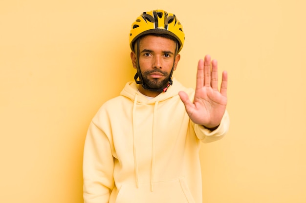 Homme afro noir regardant sérieux montrant la paume ouverte faisant le concept de vélo de geste d'arrêt