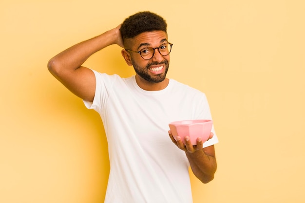 Homme afro noir se sentant stressé anxieux ou effrayé avec les mains sur la tête concept de bol vide