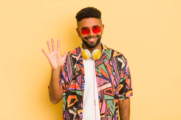 Homme afro noir souriant et amical montrant le concept de lunettes de soleil et d'écouteurs numéro cinq