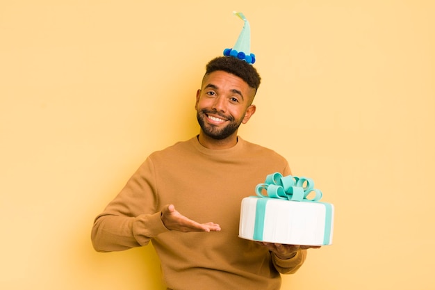 Homme afro noir souriant gaiement se sentant heureux et montrant un concept concept d'anniversaire