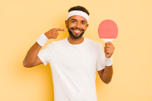 Homme afro noir souriant en toute confiance pointant vers son propre concept de ping-pong au large sourire