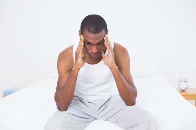 Photo homme afro souffrant de maux de tête au lit