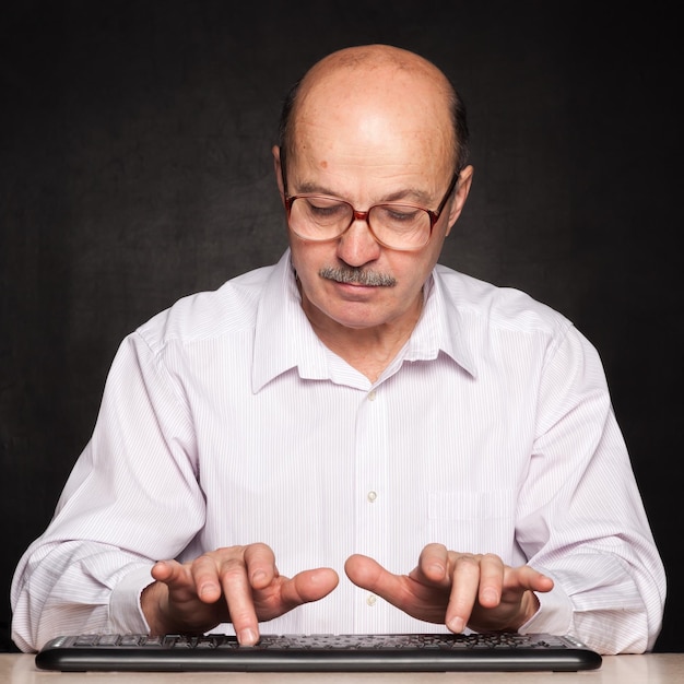 Un homme âgé apprend à taper sur un clavier avec l'index