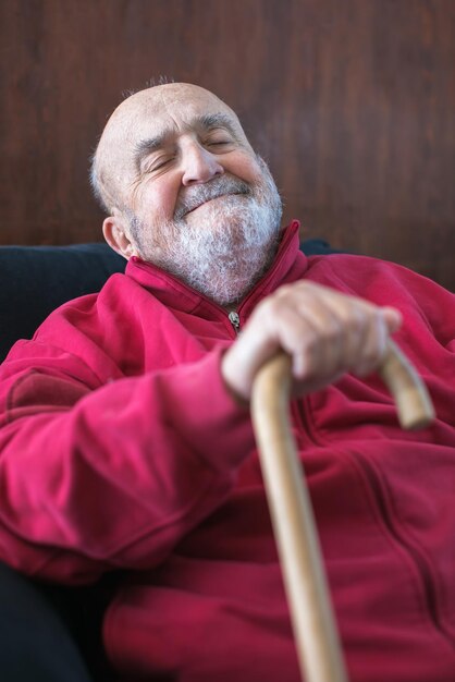 Photo un homme âgé assis avec un bâton de marche à la main