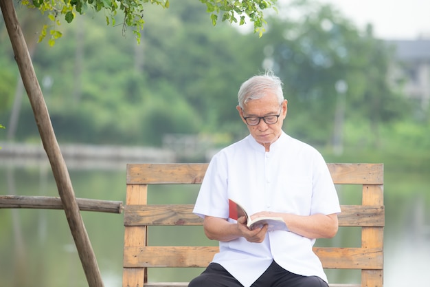 homme âgé assis et lisant dans le jardin