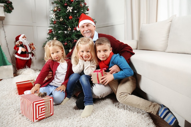 Homme âgé au chapeau de Noël avec petits-enfants à la maison