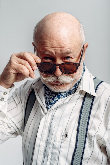 Homme âgé barbu avec moustache pose dans des lunettes de soleil. Senior mature