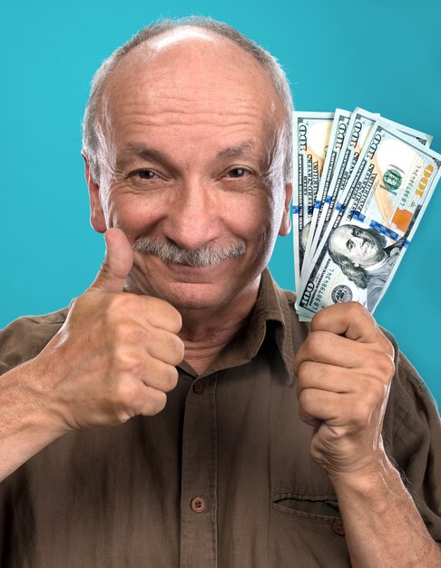 Homme âgé chanceux tenant des billets d'un dollar sur fond bleu