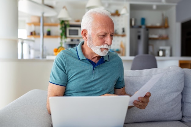 Un homme âgé concerné lit une lettre révélant des nouvelles commerciales, une invitation et un relevé bancaire Soulignant la correspondance postale et les soucis financiers dans cette image stock