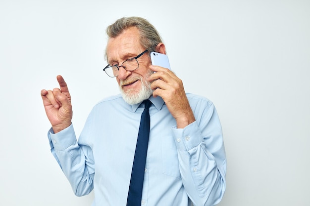 Homme âgé dans une chemise avec une cravate avec un fond clair de technologie de téléphone