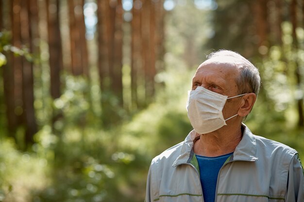 un homme âgé dans un masque de protection se promène dans le parc, une promenade en plein air après la quarantaine, une mesure de précaution contre le virus