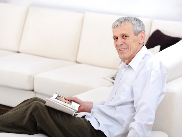 Homme âgé détendu, lecture de livre dans le salon