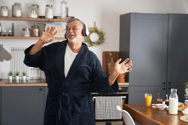 Un homme âgé avec de l'énergie qui danse et chante à la maison le matin.