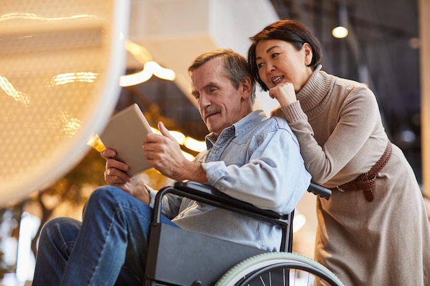 Homme âgé en fauteuil roulant à l'aide d'une application sur tablette