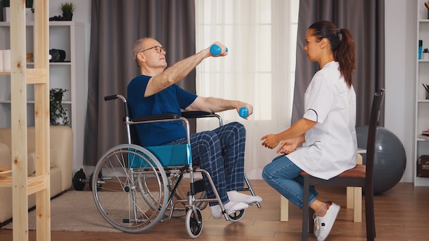 Homme âgé en fauteuil roulant faisant de l'exercice pendant la rééducation avec le soutien d'un médecin. Personne âgée handicapée handicapée avec travailleur social en thérapie de soutien au rétablissement infirmier du système de santé de physiothérapie