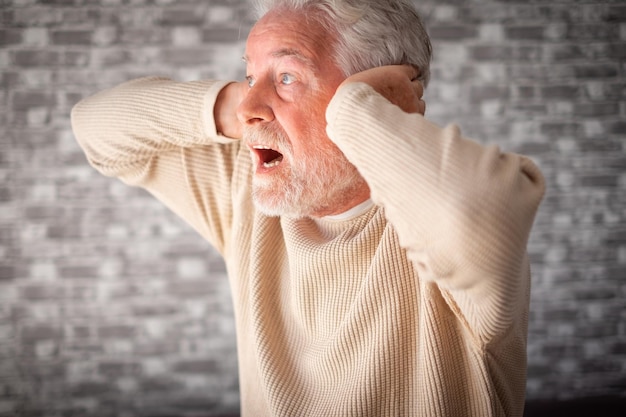 Homme âgé frustré désespéré dans la douleur avec les mains sur les oreilles assis seul à la maison homme âgé souffrant de divorce mauvaise relation maladie mentale