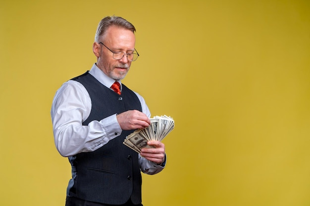 Homme âgé gagnant son argent Homme sérieux regardant les dollars Homme heureux appréciant le concept d'argent