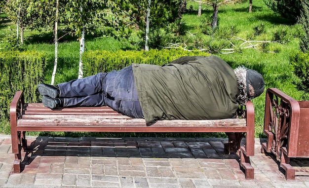 Photo un homme âgé et ivre dormant dans un parc sur un banc.