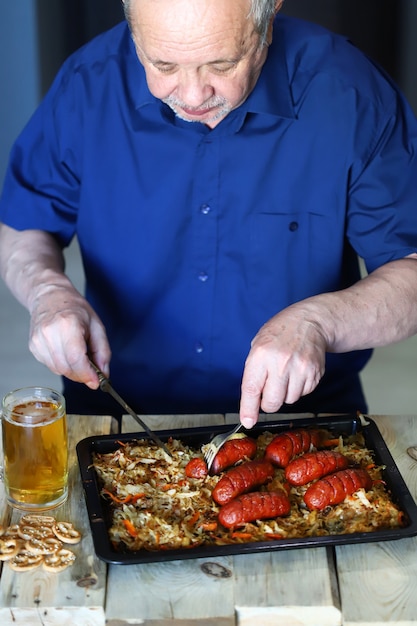 Homme âgé, manger des saucisses et boire de la bière