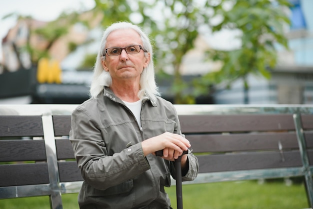 Un homme âgé marche avec une canne dans un parc de printemps de la ville