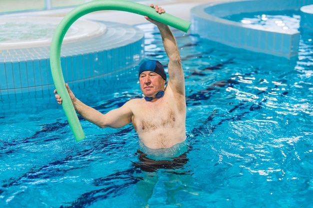 Homme âgé et mignon de race blanche faisant de l'aérobic dans la piscine concept de bien-être et de soins de santé