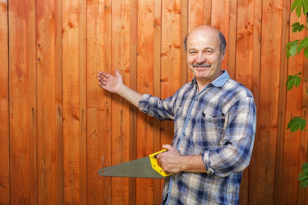 Un homme âgé avec une moustache et une tête chauve a construit un mur de planches de bois