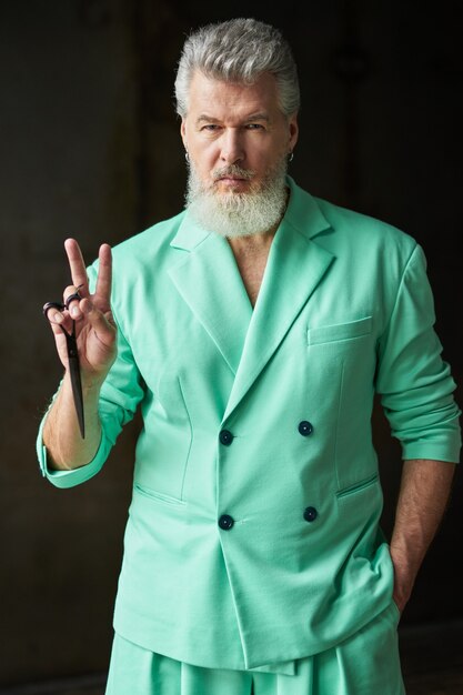 Homme d'âge moyen aux cheveux gris cool avec barbe portant une tenue colorée regardant la caméra montrant