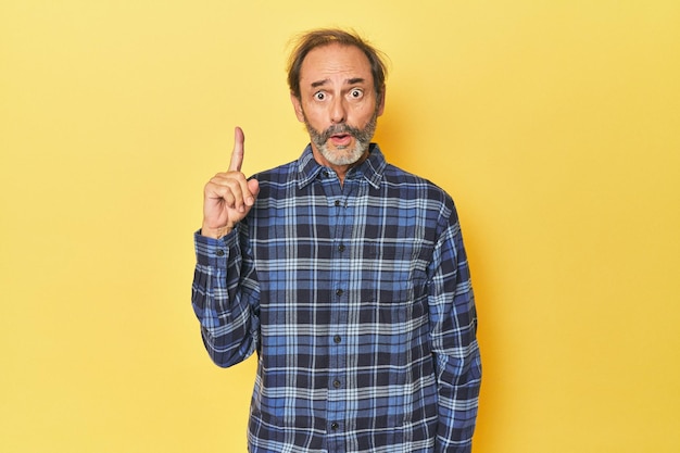 Homme d'âge moyen caucasien en studio jaune ayant un concept d'inspiration idée