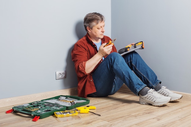 Homme d'âge moyen avec ensemble d'outils de réparation sur plancher en bois