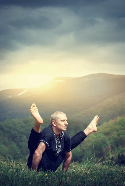 Un homme d'âge moyen faisant une pose de yoga dans la nature de la montagne