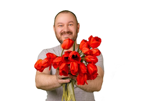 Homme d'âge moyen heureux mal rasé tenant un bouquet de fleurs de tulipes rouges et un geste d'approbation avec l'autre main sur un fond vert Célébrez le concept d'excuse