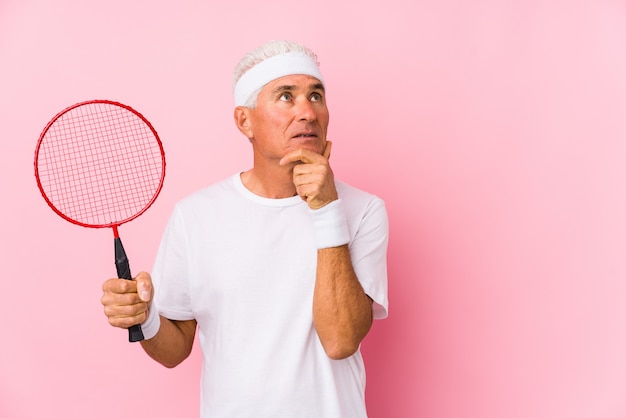 Homme d'âge moyen jouant au badminton isolé regardant de côté avec une expression douteuse et sceptique.