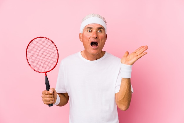 Homme d'âge moyen jouant au badminton isolé surpris et choqué.